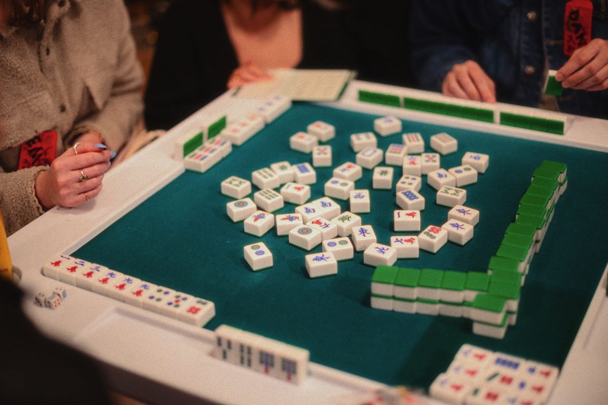 Mahjong tiles on a green-felt table mid-game