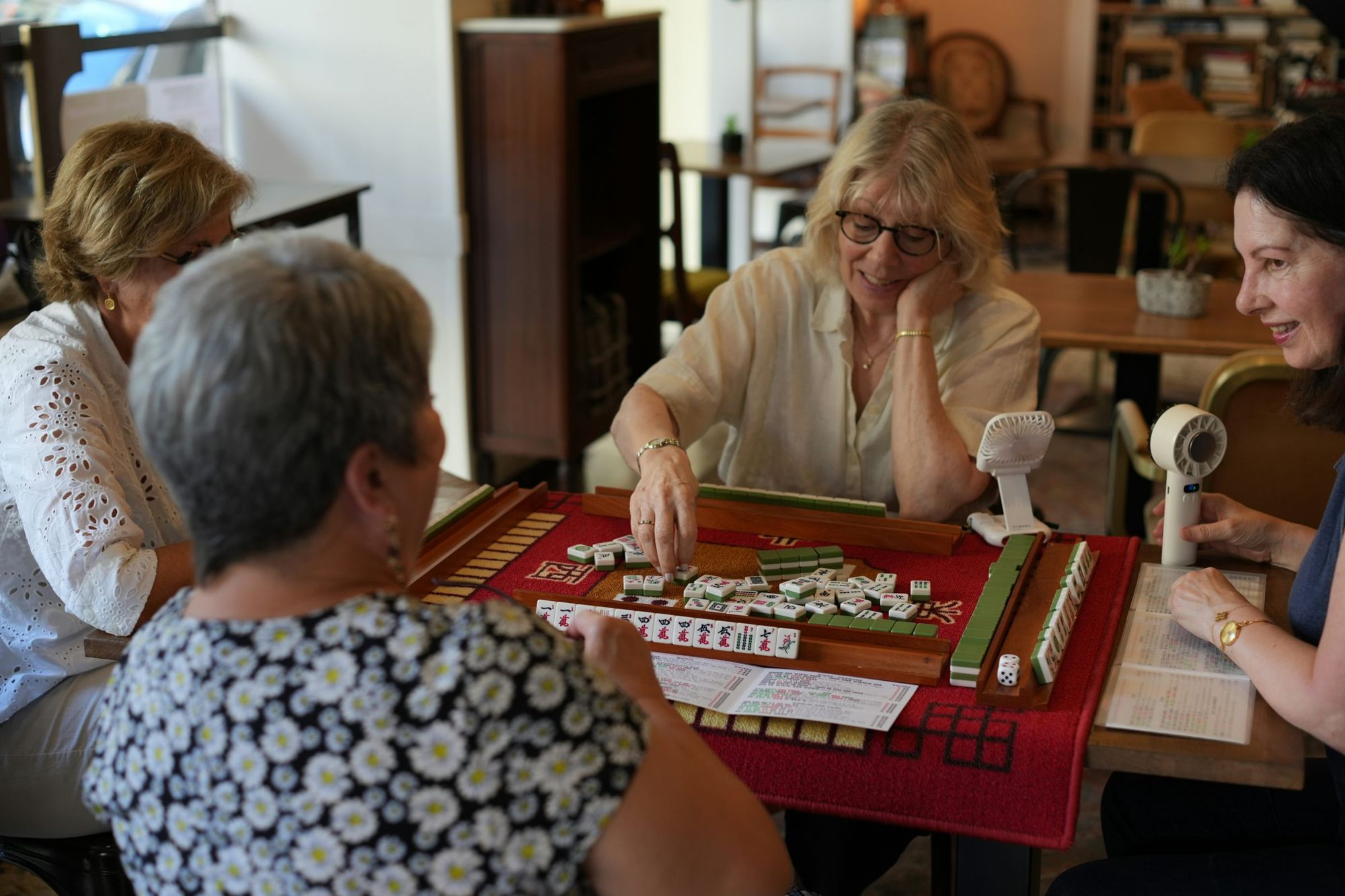 Four friends laughing over a game of mahjong